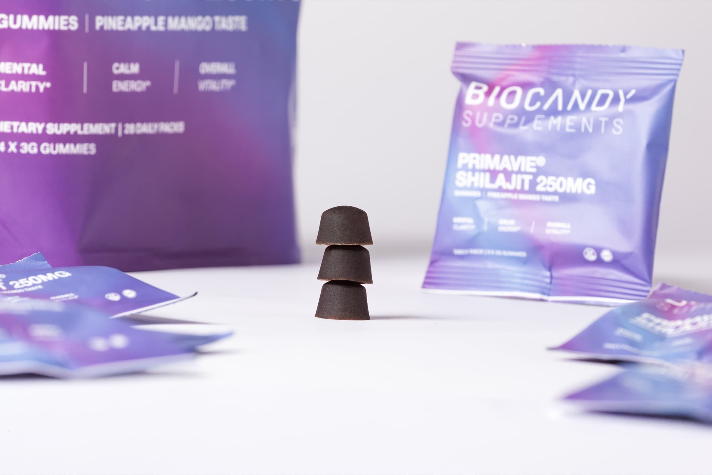 Three BioCandy shilajit gummies stacked beside daily packs