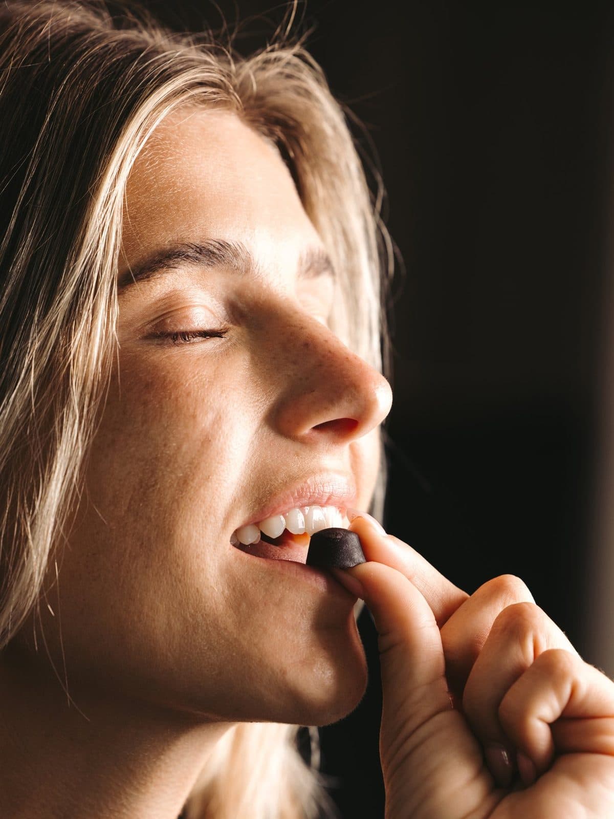 A woman savoring a BioCandy PrimaVie Shilajit gummy with her eyes closed