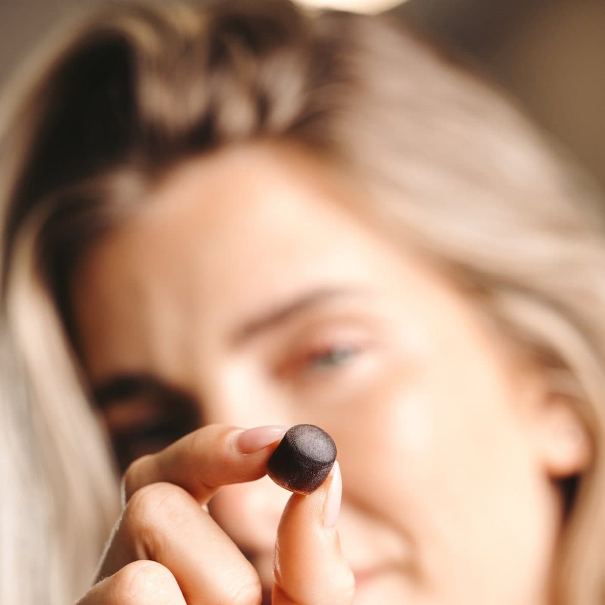 A woman holding up a single BioCandy PrimaVie Shilajit gummy